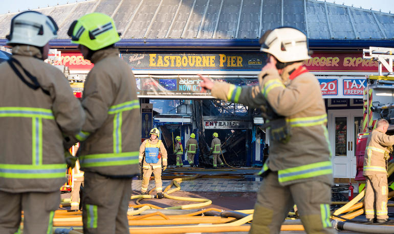 Fire fighters from East Sussex Fire and Rescue Service dampen down the flames following a large fire on the pier in Eastbourne. (Telent)